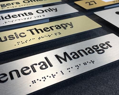 Brushed metal braille and tactile signs